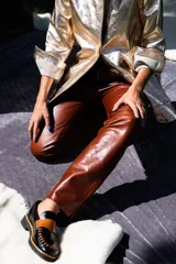 Mocasines de cuero en color dorado con detalles en marrón, con diseño bicolor y costuras artesanales expuestas en el empeine.