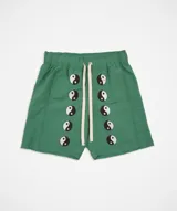 Short de baño verde con estampado de símbolos de yin y yang en blanco y negro. Tiene cintura elástica ajustable con cordón, bolsillos laterales y traseros, y logo bordado.