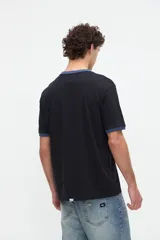 Remera negra de manga corta con cuello redondo y puños en contraste de color azul, con estampa frontal temática de pádel.