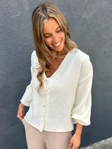 Sobrecamisa de viscosa con detalles de lúrex, color marfil, con escote en V, cierre frontal abotonado y mangas abullonadas.