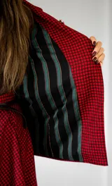 Blazer de lana con estampado de cuadros vichy en tonos rojo y marrón, solapas clásicas, dos bolsillos delanteros y cierre frontal de botones.