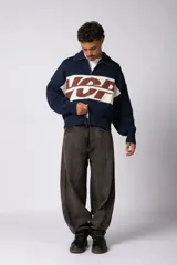 Campera tejida de punto con cierre frontal completo, cuello tipo polo y diseño con franja horizontal en contraste con estampado gráfico. Presenta puños y ruedo acanalados, con corte holgado.