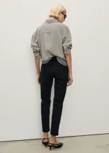 Jeans mom fit de tiro alto y corte recto, confeccionados en denim negro con tejido elástico. Cuentan con diseño clásico de cinco bolsillos, trabillas para cinturón y cierre frontal con cremallera y botón metálico.