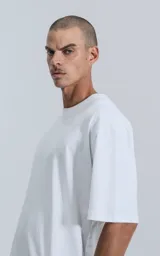 Remera de corte oversize y largo cropped, confeccionada en algodón premium. Presenta cuello redondo, mangas cortas con hombros caídos y un calce relajado.