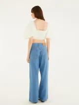 Pantalón de jean celeste, de corte wide leg y tiro medio, con cordones entrelazados a lo largo de los laterales.