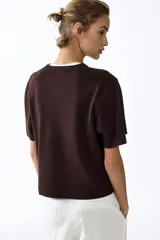 Remera de punto color marrón oscuro, de textura tupida, con cuello redondo acanalado, mangas cortas con hombros caídos y bajo recto.