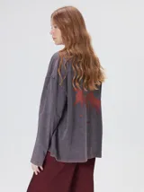 Remera oversize de manga larga color naranja con efecto gastado, cuello redondo y gráfico estampado en la espalda.