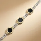 Pulsera de diseño articulado compuesta por eslabones de plata texturizada con detalles en oro y piedras circulares de ónix negro. El conjunto incluye además dos brazaletes rígidos complementarios en plata y oro.