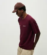Remera de corte oversized color bordó, con cuello redondo y manga corta. Presenta un estampado en la espalda con lettering manuscrito que incluye las ciudades Paris, Tokyo y New York, junto con detalles tipográficos adicionales.