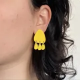 Par de aros colgantes plateados con forma triangular y tres dijes redondos colgando de la base.