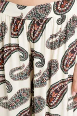 Pantalón de corte fluido color beige con estampado paisley en tonos oscuros, tiro alto con lazo para anudar en la cintura y botamangas con elástico.