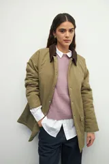 Campera color verde militar con cuello de pana marrón, bolsillos con solapa y botones metálicos. Interior forrado con tela satinada capitoneada.