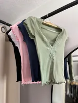 Remera corta color verde agua, con escote en V y detalle de puntilla blanca en el borde.