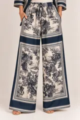 Palazzo amplio de seda con estampado paisajístico y bordes en tono azul marino. Cuenta con cintura elástica con cordón ajustable y bolsillos laterales.