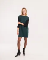 Vestido corto negro con mangas 3/4 verdes, cuello bote y bolsillos laterales.