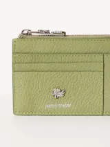 Tarjetero de cuero vacuno color verde oliva, con cierre superior y aplique metálico de flor en el frente.