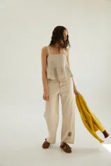 Pantalón de corte recto y tiro medio con costuras a la vista, bolsillos delanteros y traseros, y un detalle de pin de la marca en el ruedo.