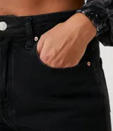 Pantalón mom jeans negro de tiro alto con trabillas anchas, bolsillos y bajo doblado. Confeccionado en algodón responsable.