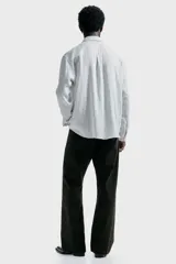 Camisa blanca de manga larga con rayas verticales finas en gris, cuello inglés, tapeta clásica de botones y bajo redondeado.