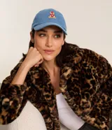 Gorra de visera curva confeccionada en jean de algodón, color celeste, con diseño de osito bordado en el frente y cierre ajustable en la parte posterior.