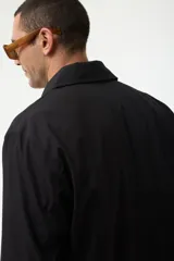 Gabardina azul marino con cuello clásico, cierre frontal con botones y bolsillos laterales.