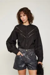 Camisa negra de manga larga estilo globo, justa al cuerpo con detalles de aberturas pequeñas que generan una trama en el pecho y en las mangas.