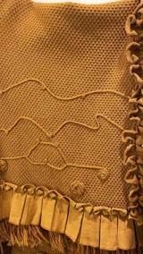 Ruana de tejido con textura en color bordó, con diseño amplio y fluido. Presenta detalles de volados aplicados en el cuello y ruedo, terminaciones con flecos y lazo frontal regulable.