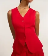 Chaleco de vestir color blanco hueso, con escote en V, cierre frontal con botones y espalda abierta. Corte sastrero.