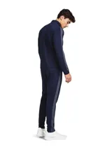 Conjunto deportivo Under Armour Rival Knit compuesto por campera y pantalón, en color azul marino. La campera cuenta con cierre frontal completo, cuello alto y bolsillos laterales, mientras que el pantalón presenta cintura elástica ajustable con cordón y bolsillos laterales de malla. Ambos elementos tienen detalles de franjas grises en los laterales y el logo de la marca estampado en tono contrastante.