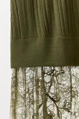 Vestido midi de punto acanalado color verde oliva, con escote en V y tirantes anchos. La parte superior presenta un diseño de tejido rib, mientras que la parte inferior está terminada con una aplicación de encaje transparente al tono.