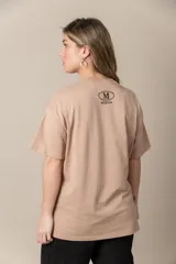 Remera gris con estampa de la letra M en negro y cadena plateada en el cuello.