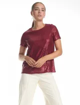 Blusa de manga corta con cuello redondo, confeccionada en tejido cubierto de lentejuelas color verde esmeralda. Cuenta con forro interno a tono y un corte recto.