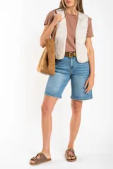 Chaleco sin mangas, color beige claro, con bordados florales en relieve y ribetes a contraste.