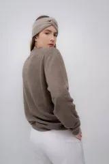 Vincha de lana color beige, tejida a mano, con diseño trenzado en el frente.