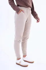 Pantalón de jogging de felpa, color beige, con cintura elástica ajustable mediante cordón y puños acanalados en los tobillos.