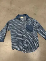 Camisa de jean oversized color azul, con botones rojos y costuras en contraste rojo. Tiene un bolsillo en el pecho.