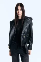 Campera de cuero ovino con capucha amplia integrada, cruce asimétrico con cierre metálico y cinturón regulable en la cintura. Presenta mangas largas con cierres metálicos en los puños y diseño estructurado.