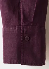 Camisa de lino color bordó con cuello camisero, manga larga con puños abotonados, bolsillo aplicado en el pecho y cierre frontal de botones.