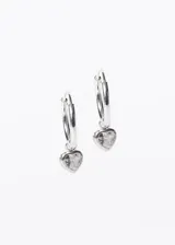 Par de aros tipo argolla de plata con dije colgante en forma de corazón con incrustaciones de zirconia blanca.