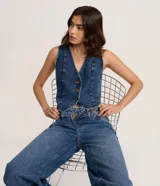 Chaleco de jean con escote en V, cierre frontal con botones metálicos y ruedo redondeado. Presenta un diseño clásico con lazo ajustable en la espalda.