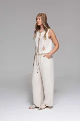 Pantalón ancho de tiro alto, color beige claro, con cintura elastizada y cordón ajustable. Presenta bolsillos laterales.
