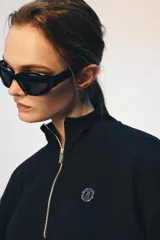 Sudadera de algodón con cuello alto y cierre frontal de cremallera metálica dorada. Presenta manga larga con puños elásticos, bajo elástico y detalle de logo metálico en el pecho.