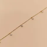 Pulsera de cadena fina en oro 18k con dijes de circonias engarzadas distribuidos a lo largo de la misma.