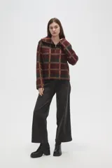 Sweater de tejido jacquard con diseño a cuadros en tonos bordó, negro y beige. Presenta un corte holgado, cuello solapa amplio y cierre frontal parcial con cremallera.