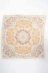 Pañuelo cuadrado de poliéster con estampado tipo paisley y floral en tonos celestes, blancos, rosados y anaranjados.