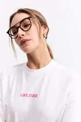 Remera de algodón blanca con cuello redondo y corte relajado. Presenta un estampado frontal con la frase 'LIKE, EVER' en color rosa y 'everyday colours' en verde claro.