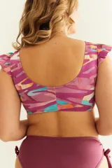 Top de bikini con estampado abstracto en tonos morado, naranja, celeste y blanco. Tiene volados en los hombros y nudo regulable en el escote.