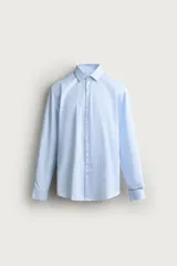 Camisa slim fit de algodón color celeste con sutil patrón de cuadros, cuello clásico y manga larga con puños abotonados.