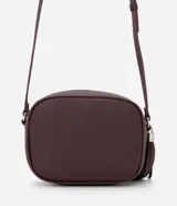 Cartera bandolera pequeña de diseño estructurado en color topo, con cierre de cremallera metálico y detalle de borla larga colgante. Cuenta con correa ajustable y forro interior.