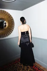 Top de tafeta negra con leve brillo, diseño al cuerpo con cuello halter, drapeados en el busto y un delicado volado en el borde inferior.